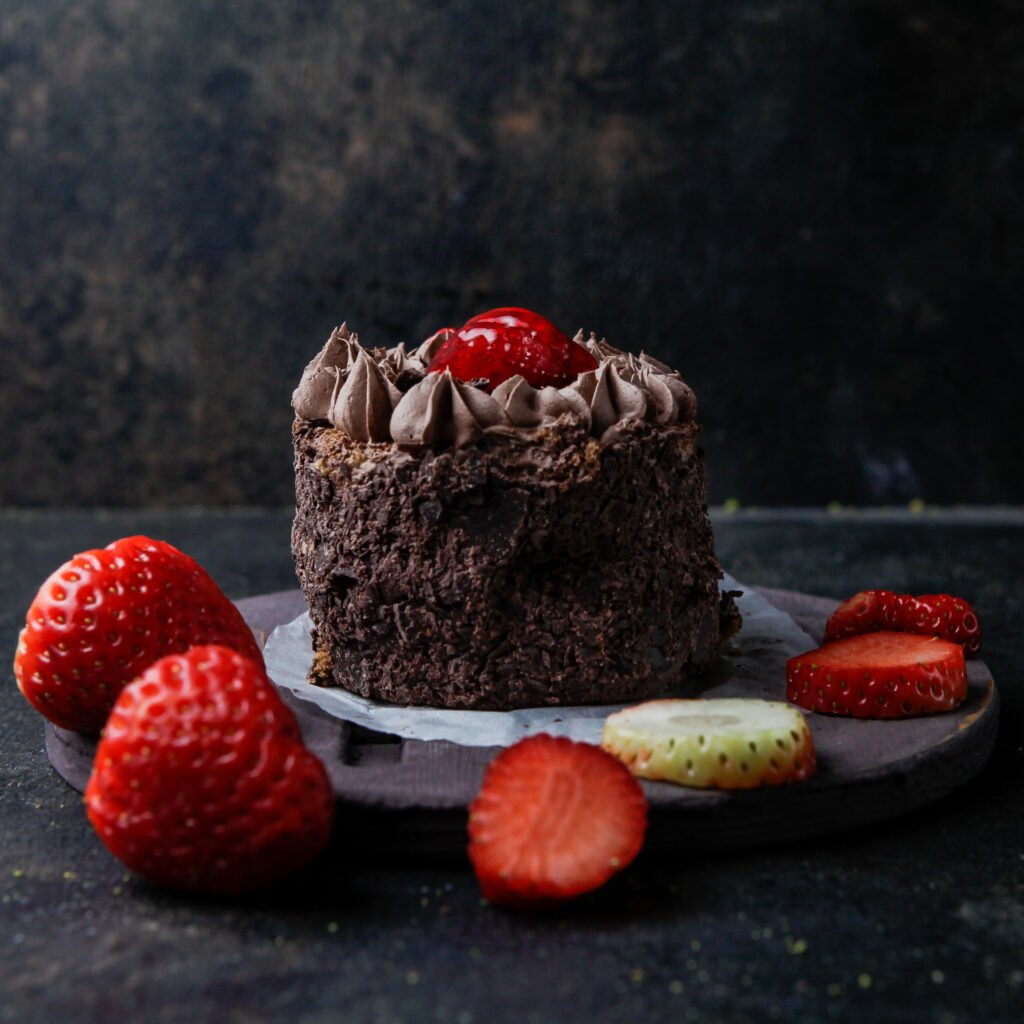 side vew chocolate cake with strawberry in round plate on stone background